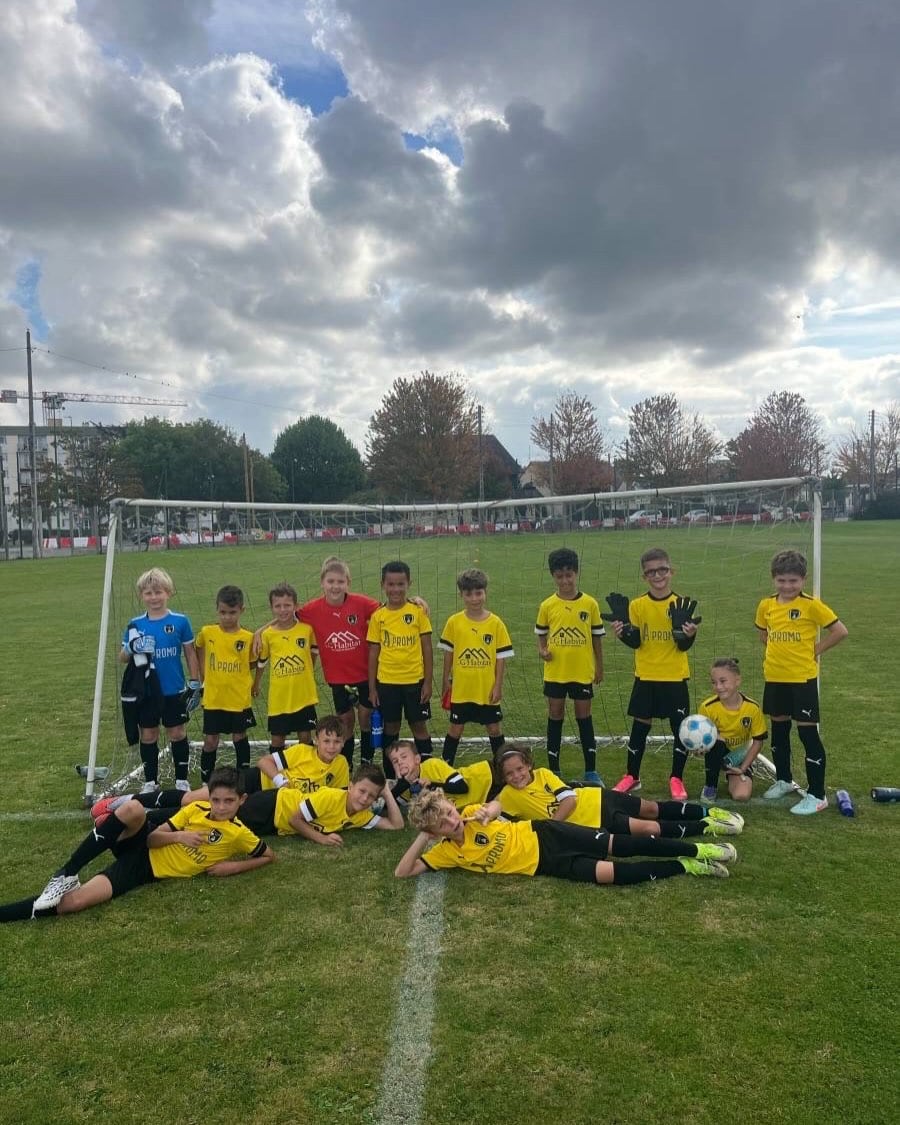 De jeunes joueurs de l'ASPTT Caen posent devant le but, en maillot jaune et noir