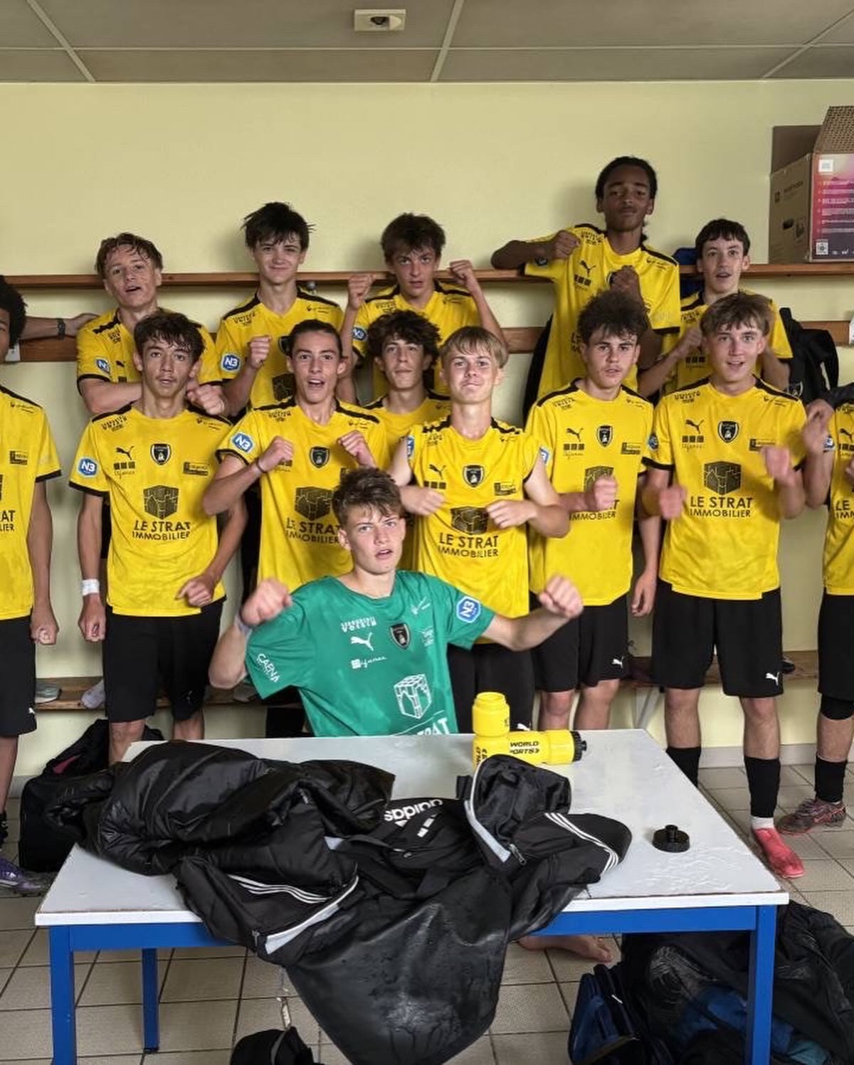 Une équipe de jeunes de l'ASPTT Caen, en maillot jaune, fête une victoire dans le vestiaire