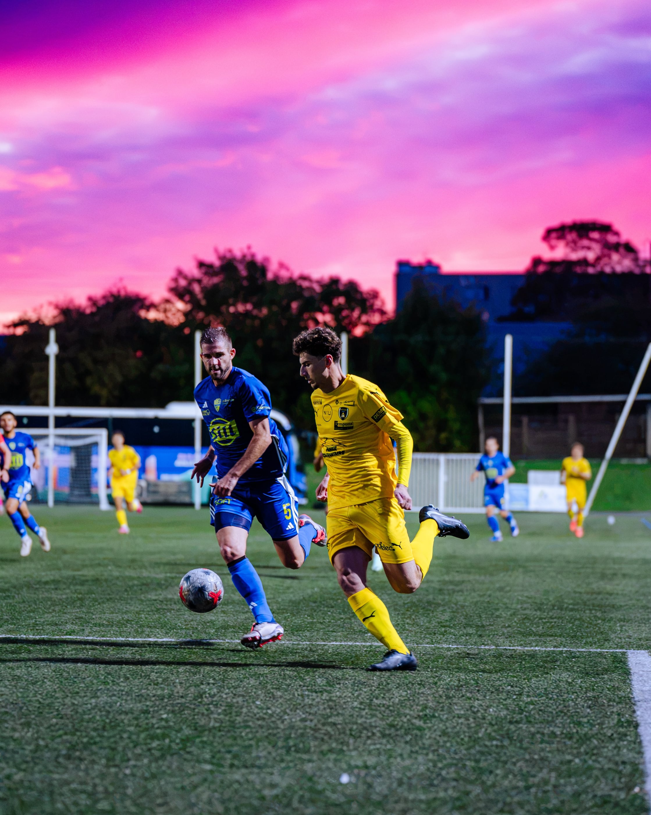 Action de jeu de l'équipe première de l'ASPTT Caen en National 2 sous un ciel rose de fin de journée