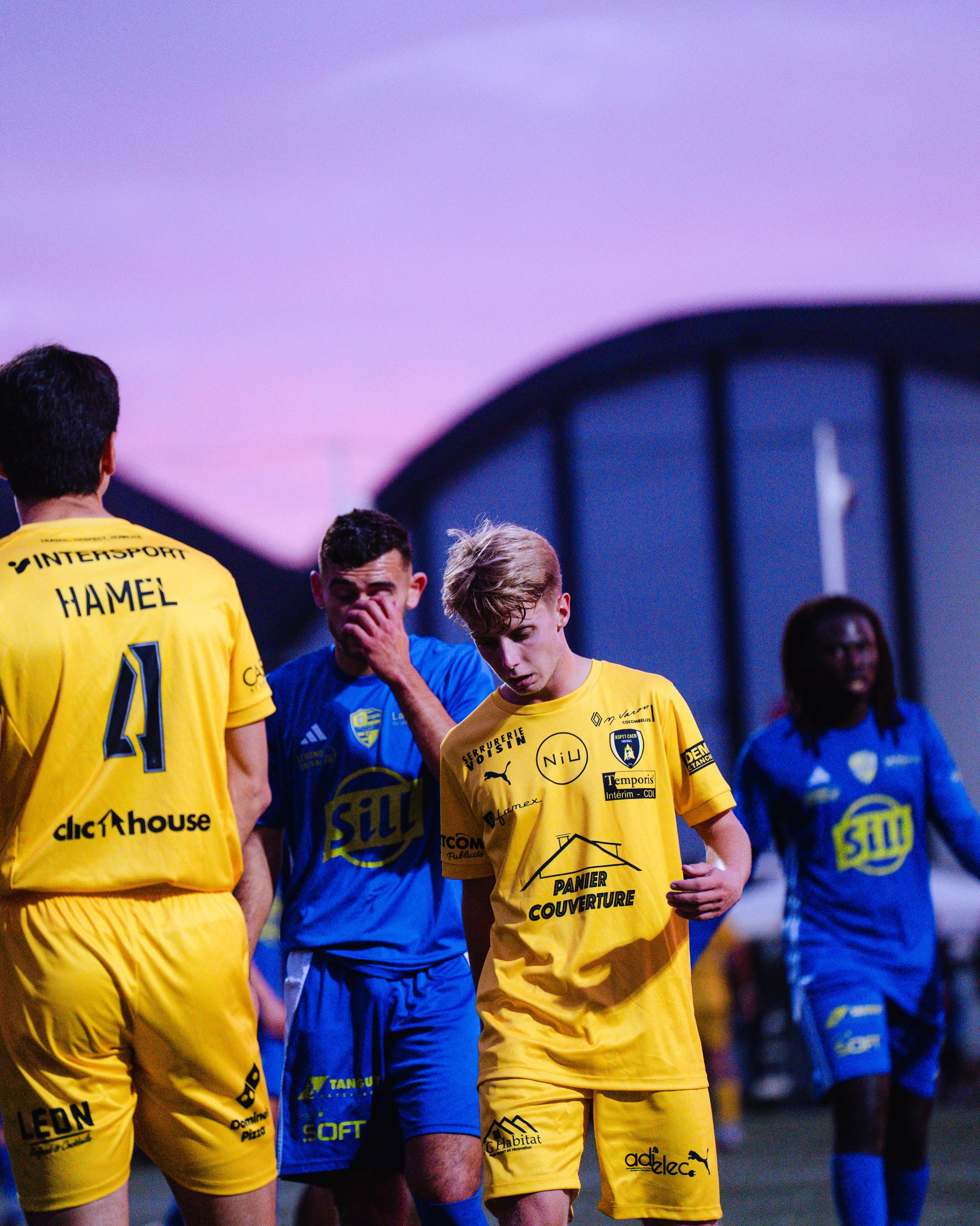 Des joueurs de l'ASPTT Caen, dont Hamel n° 4, pendant un match de National 2 à la Hache, sous un ciel violet