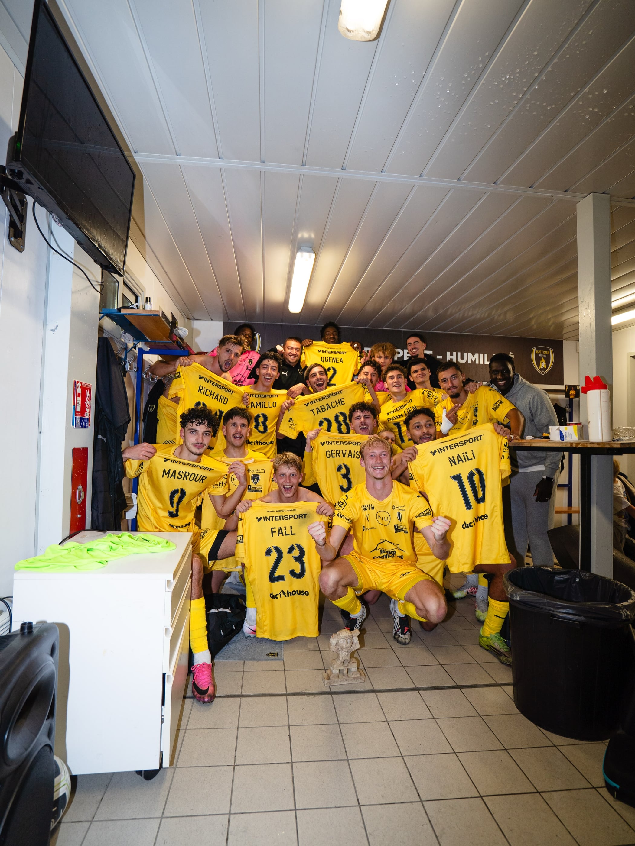 L'équipe première de l'ASPTT Caen fête dans le vestiaire sa victoire 2-1 contre Milizac en National 2, maillots brandis